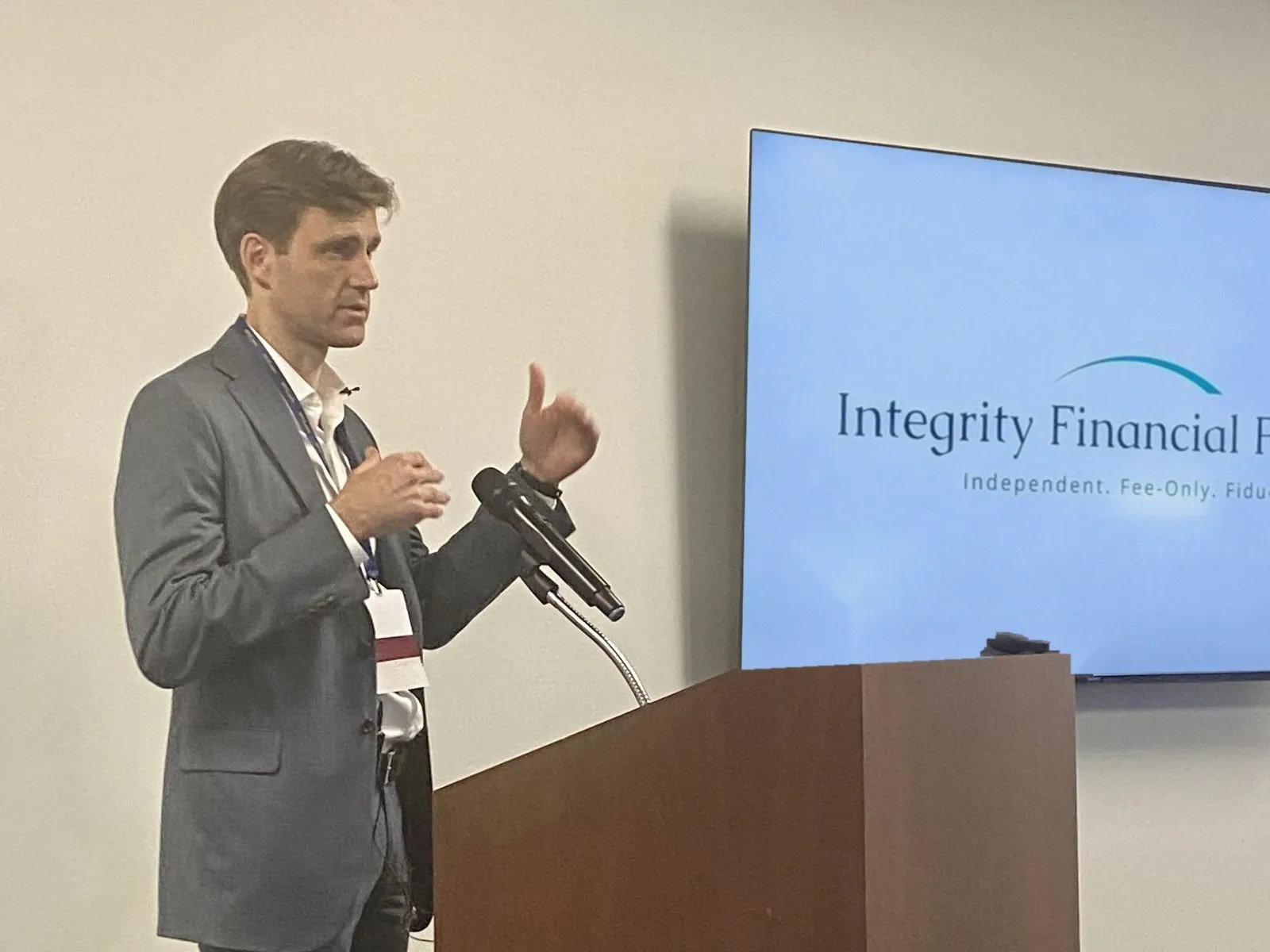 Ryan Firth presenting at a podium with the Integrity Financial Planning logo on screen